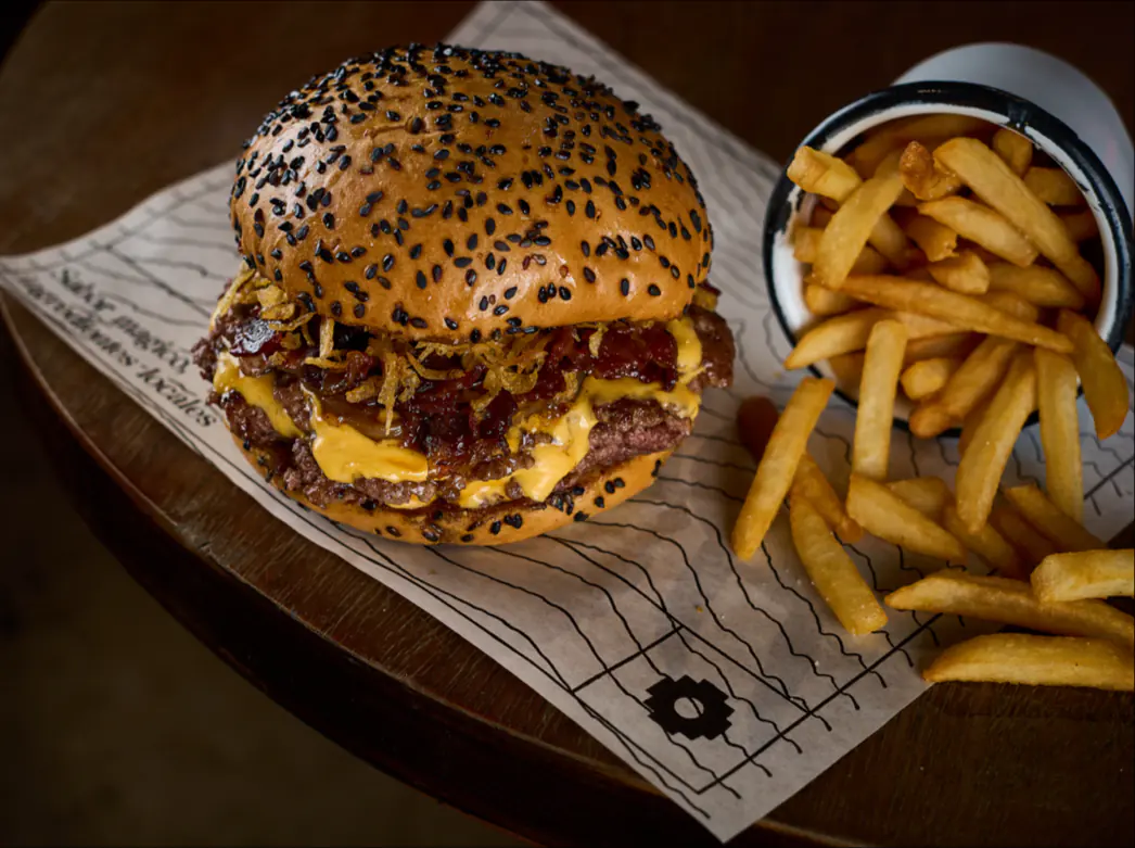 Smash burger doble con queso y papas a la francesa sobre papel de Andes
